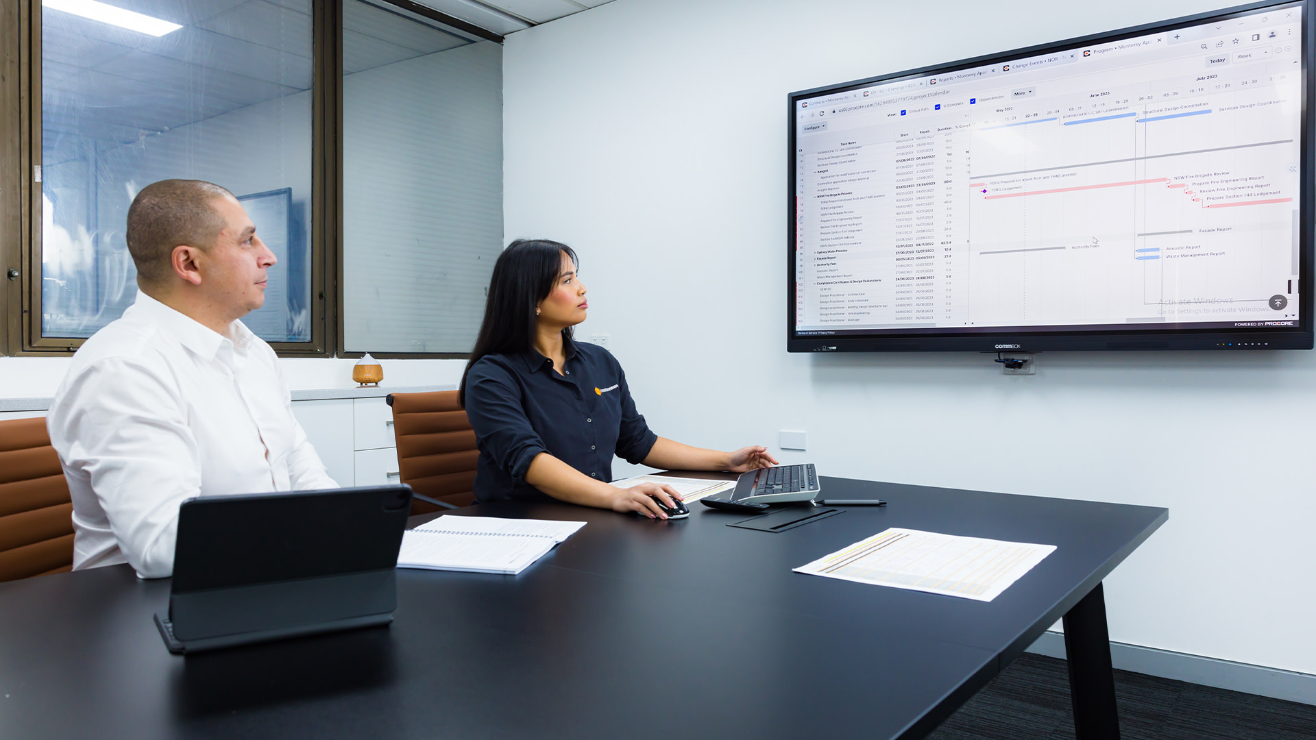 A woman and a man looking at a screen in a meeting room