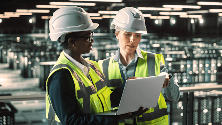 Two women wearing safety gear at a data center
